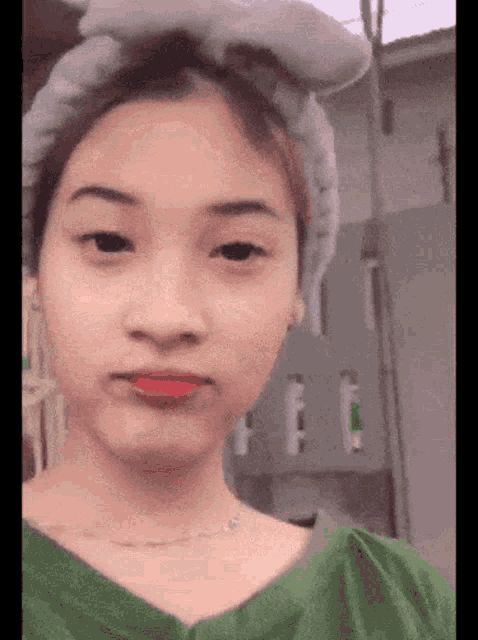 a girl with a headband on her head is making a face .