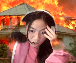 a girl wearing headphones is standing in front of a burning house