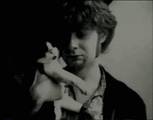 a man with a beard is holding a cat in his arms .