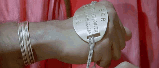 a person 's wrist is chained to a plaque that says scr on it
