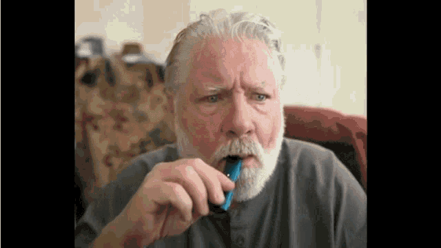 a man with a beard is brushing his teeth with a toothbrush