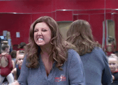 a woman is making a funny face while standing in front of a mirror .