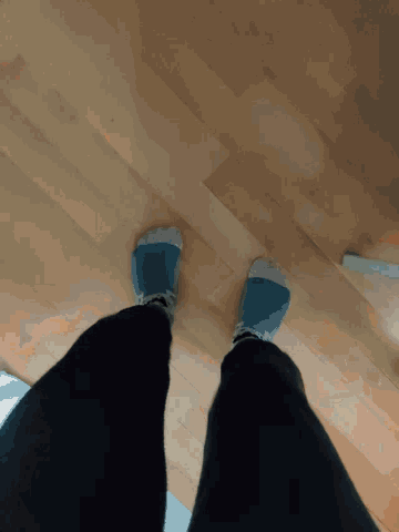 a person wearing blue and green socks standing on a wood floor