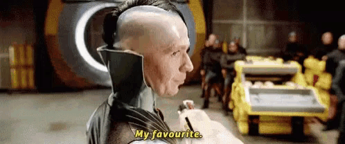 a man with a mohawk is holding a pen and saying `` my favourite '' in front of a group of people .