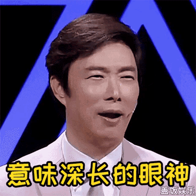 a man in a pink suit and tie is making a funny face with chinese writing behind him