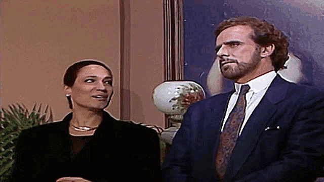 a man and a woman are standing next to each other in front of a picture