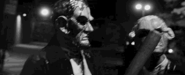 a black and white photo of two men wearing masks and holding a bat .