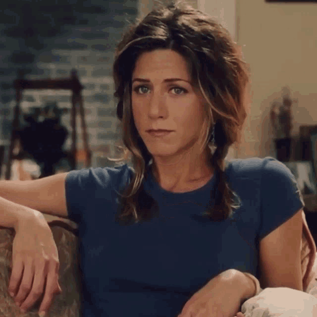 a woman wearing a blue shirt is sitting on a couch