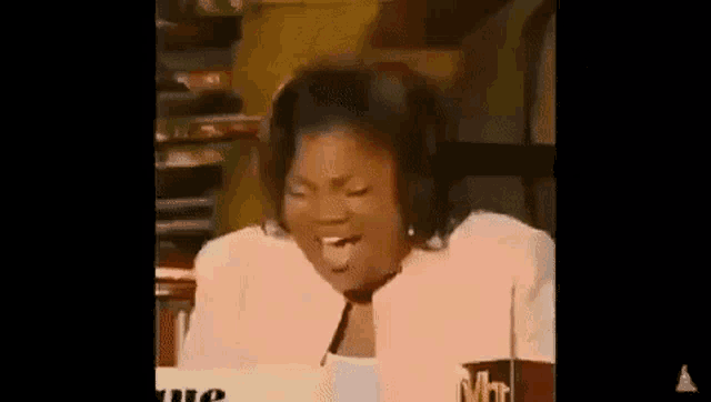 a woman is sitting at a table making a funny face .