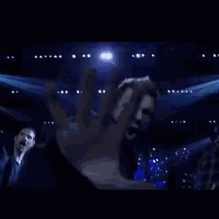 a group of men are dancing on a stage in front of a blue background .