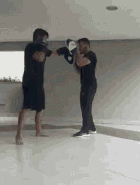 two men are boxing in a room with a white floor .
