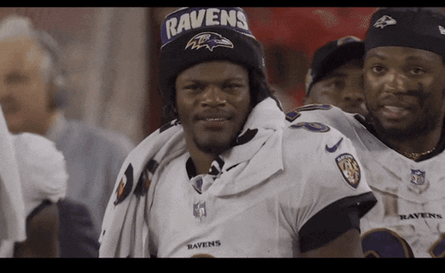 a man wearing a ravens hat stands next to another man wearing a ravens jersey