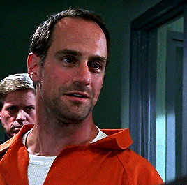 a man in an orange uniform stands in a hallway