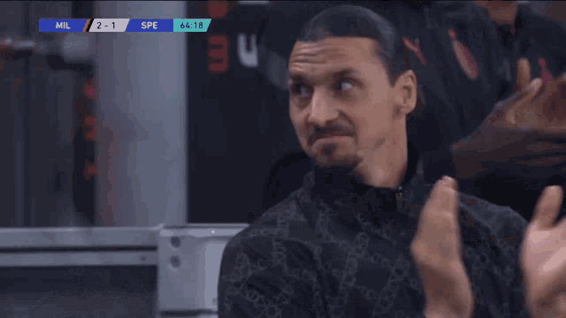 a man applauds in front of a scoreboard that says mil 2-1
