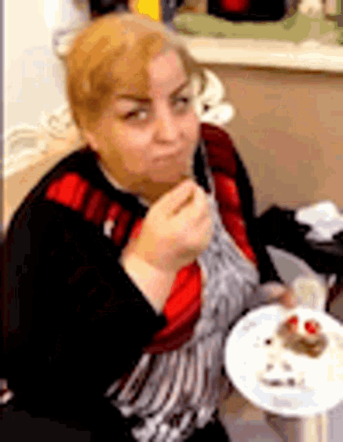 a woman is sitting at a table with a plate of food and a fork in her hand .