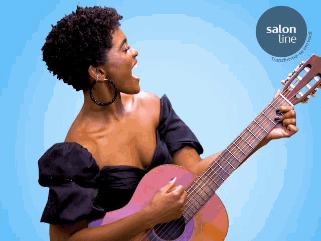 a woman singing while holding a guitar with a salon line logo behind her