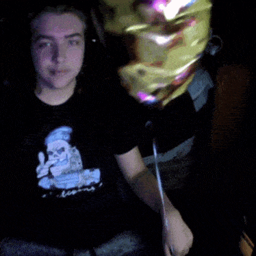 a man in a black shirt holds a birthday balloon in front of him