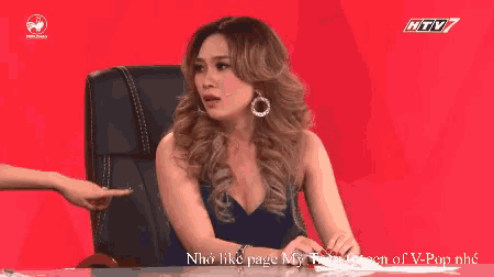 a woman in a blue dress is sitting in a chair and talking to another woman on a tv show