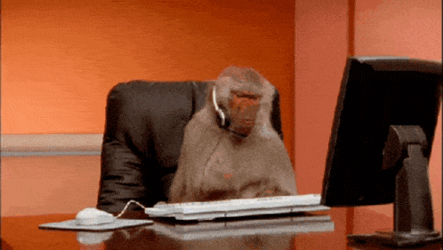 a monkey wearing a headset is sitting at a desk in front of a computer