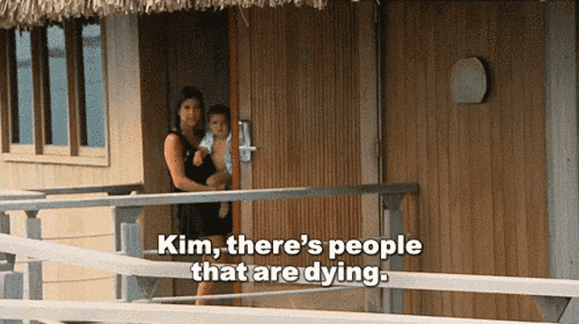 a woman holding a child on a balcony with the words kim there 's people that are dying