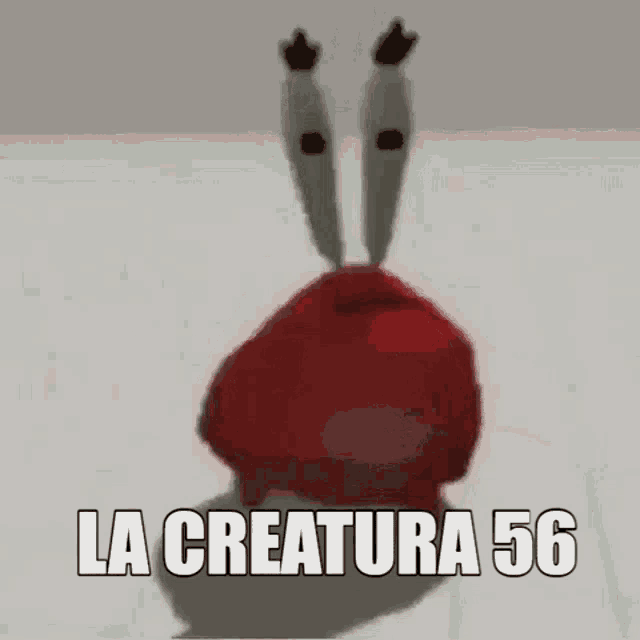 a crab from spongebob squarepants is standing on a white surface with the words `` la creatura 56 '' written on it .