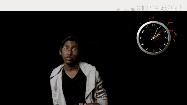 a man with glasses is standing in front of a clock that shows the time as 5:00