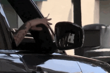 a man is driving a car with his hands out the window .