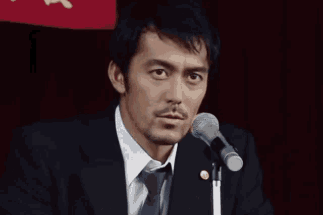 a man in a suit speaking into a microphone