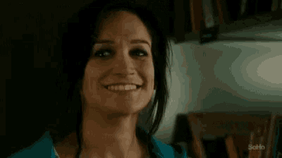 a woman in a blue shirt is laughing and looking up at the sky .