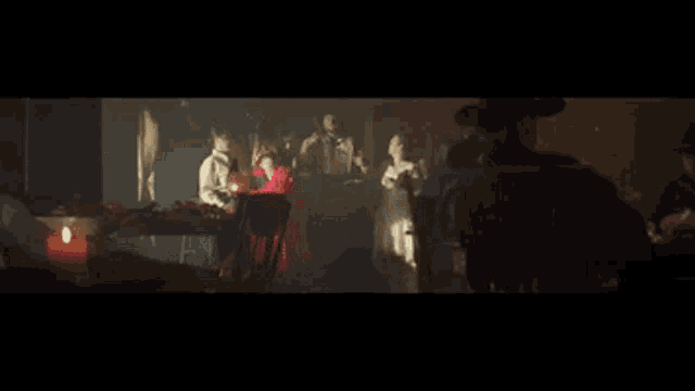 a group of people are dancing in a dark room with candles