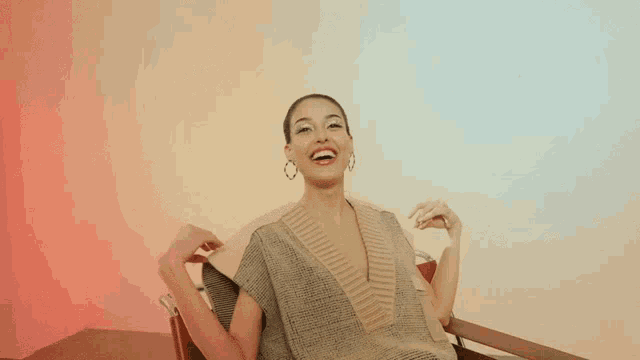 a woman sitting in a chair with her arms outstretched laughing