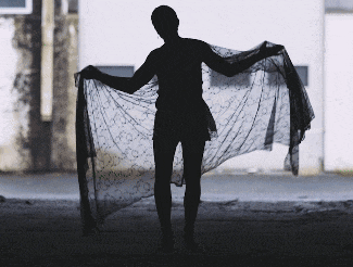 a silhouette of a woman holding a black scarf in front of a building