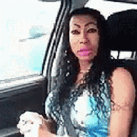 a woman is sitting in the driver 's seat of a car holding a dog .