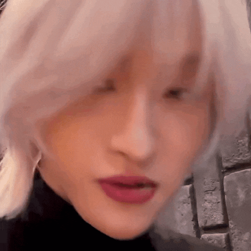 a close up of a woman 's face with blonde hair and red lips .