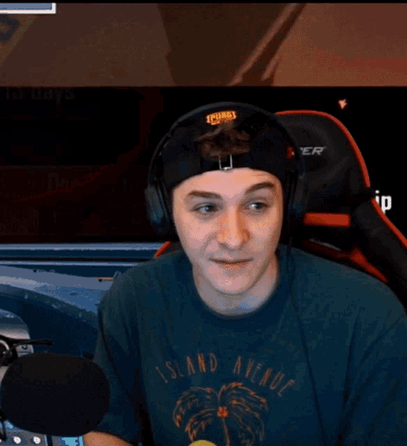a man wearing a shirt that says island avenue is sitting in front of a microphone