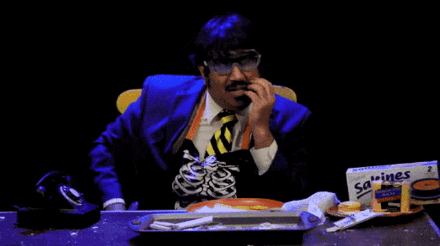 a man is sitting at a table with a box of sardines in front of him
