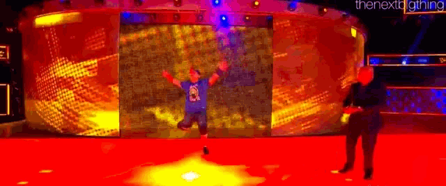 a man in a blue shirt with the number 21 on it is standing in front of a large screen on a stage .