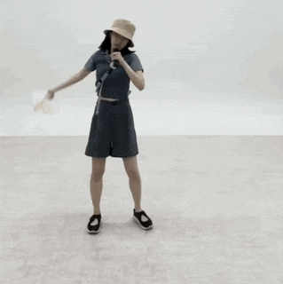 a woman wearing a bucket hat and shorts is dancing in a room .