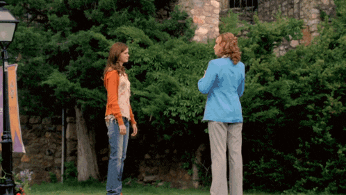 a woman in a blue jacket stands next to another woman in an orange shirt