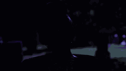a woman wearing a hat and a veil is standing in the dark .