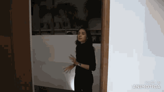 a woman in a black turtleneck sweater is standing in a dark room .