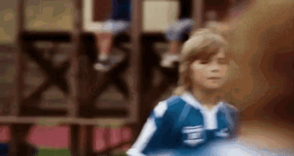 a young girl in a blue and white soccer jersey is standing in front of a crowd .
