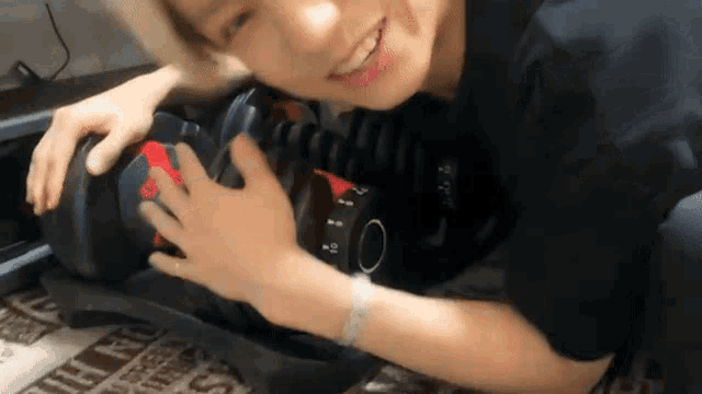 a young man is laying on the floor holding a dumbbell and smiling .