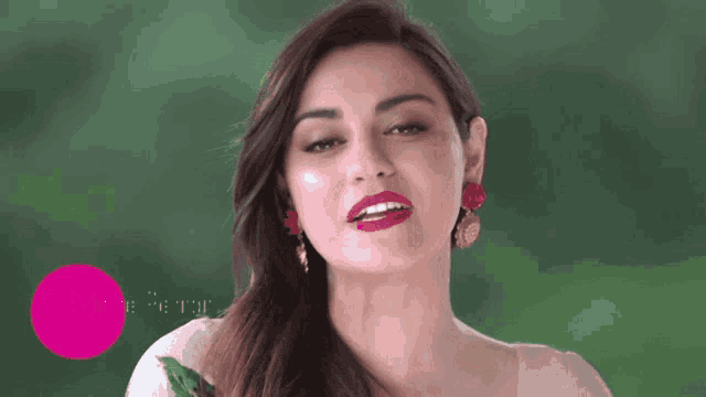 a woman in a white dress with red lipstick and earrings looks at the camera