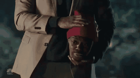 a man in a suit and tie is holding a man 's head in his hands .