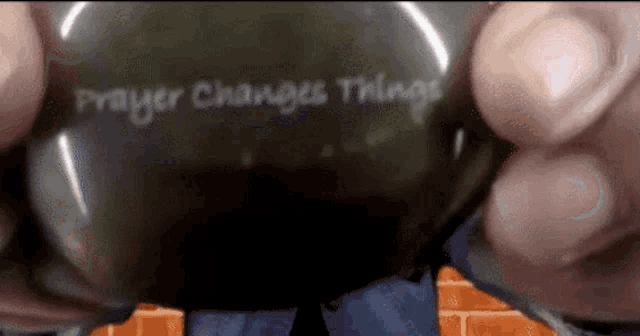 a person is holding a black object that says prayer changes things on it