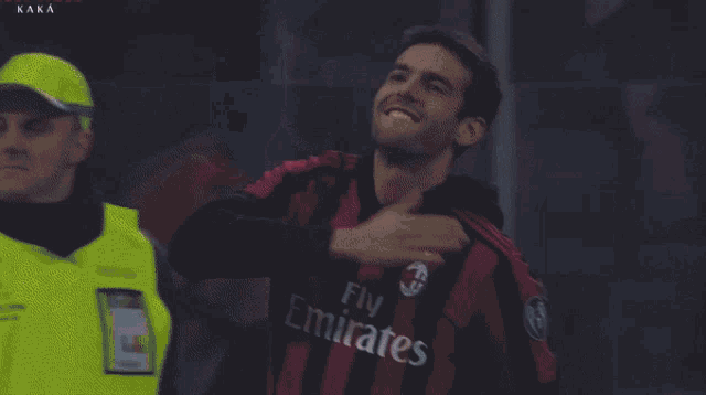 a soccer player wearing a fly emirates jersey holds his hand to his chest