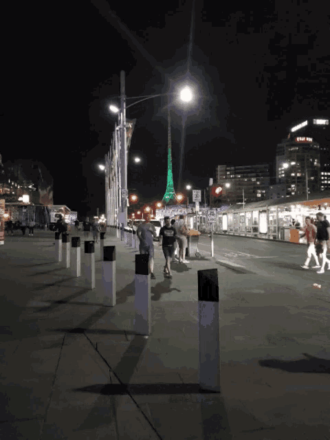 a group of people are walking down a street at night with a sign that says ' a ' on it