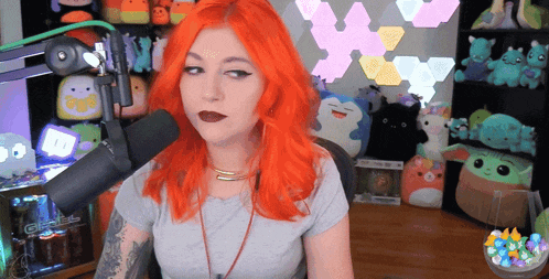 a woman with red hair is sitting in front of a microphone with a twitch logo in the background