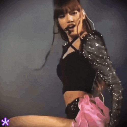 a woman in a black top and a pink skirt is dancing on a stage